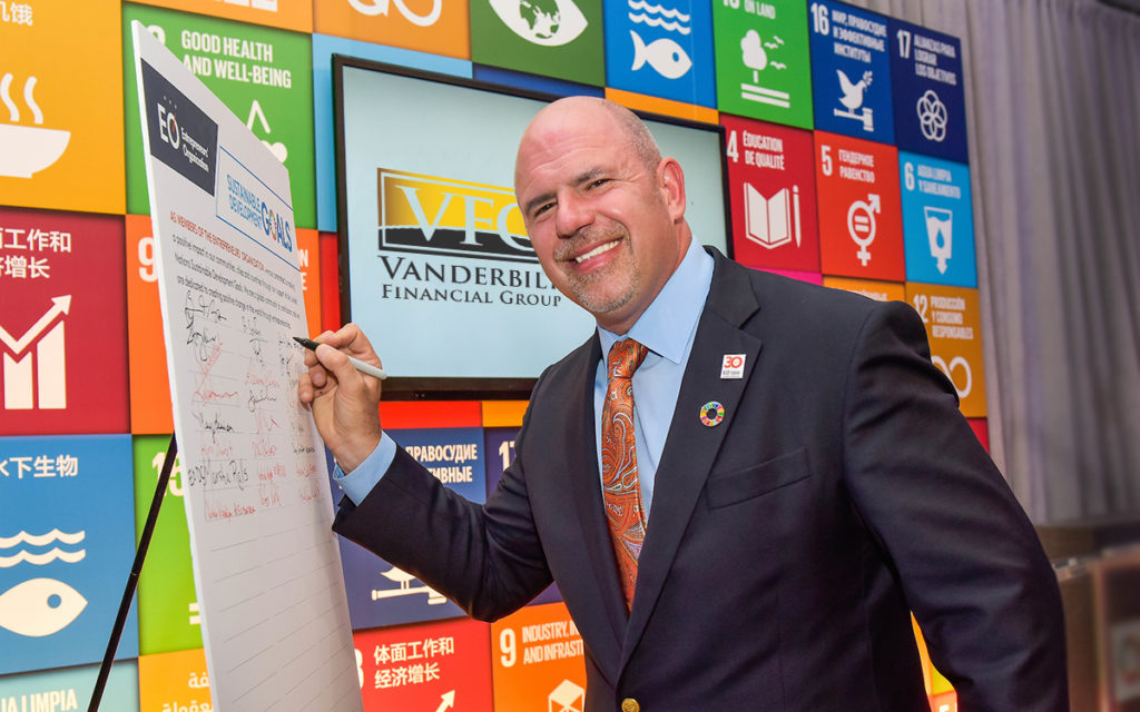 Steve Distante in front of a poster of the Sustainable Development Goals set by the United Nations