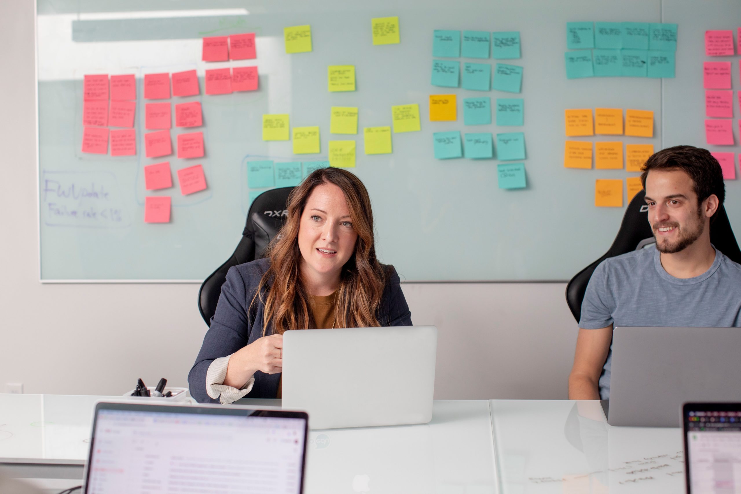 Two sales people working in a meeting with laptops