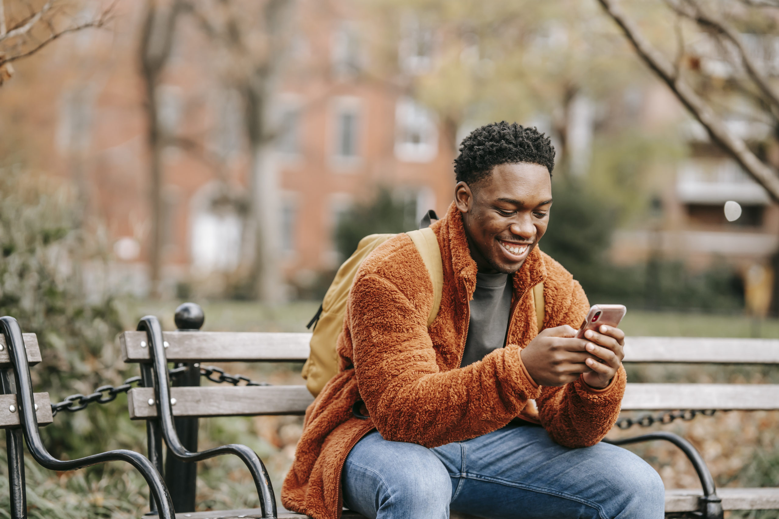 Delightful african american man surfing modern cellphone in city park